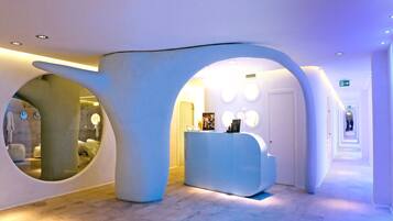 Un espace d’accueil moderne doté d’une architecture originale, avec de grandes fenêtres circulaires et un comptoir d’accueil au design minimaliste.