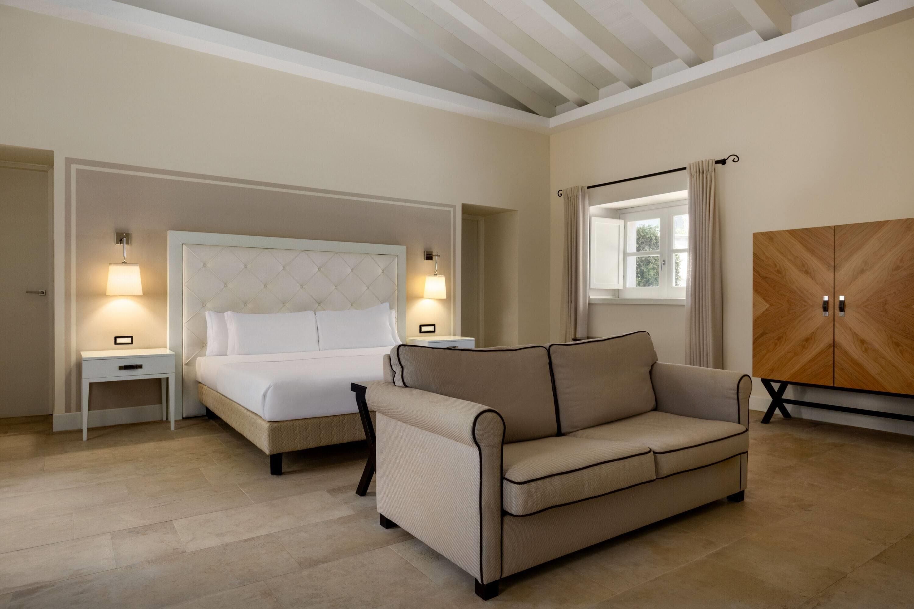 A bedroom with a bed, bedside tables, a sofa, and a wardrobe.