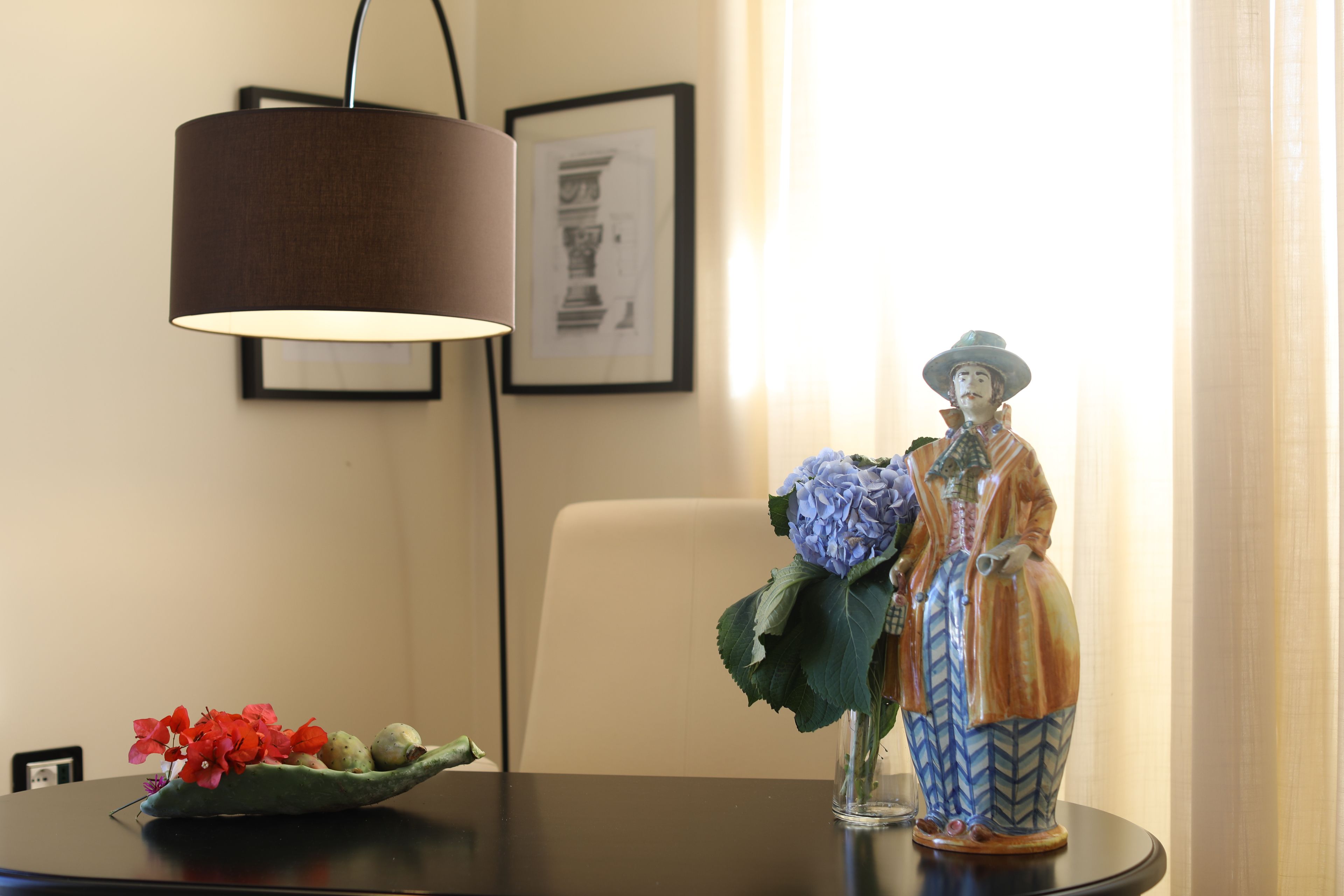 A table with a vase of flowers, a decorative figurine, and a lamp.