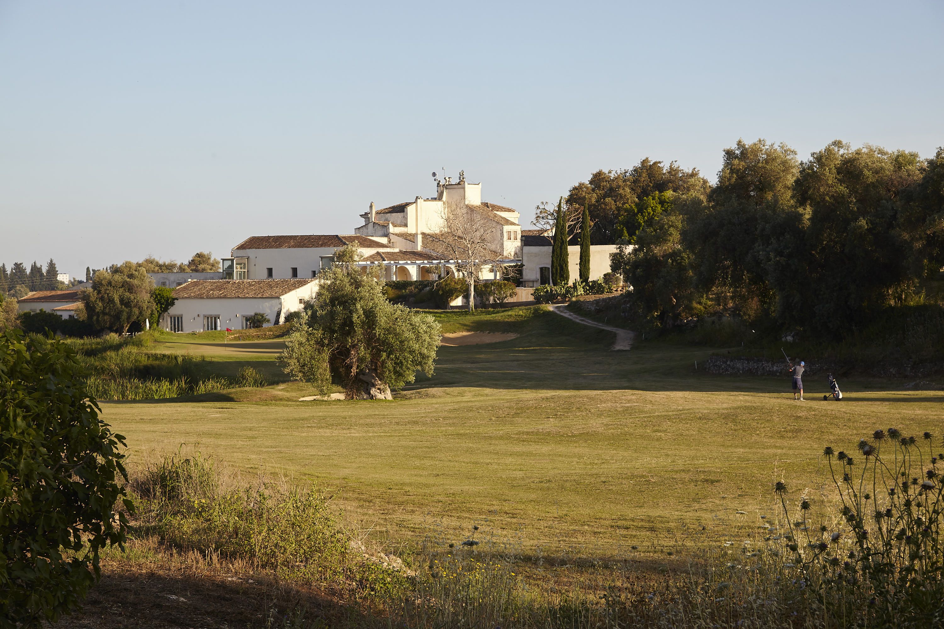 Un campo de golf con un club de campo al fondo.