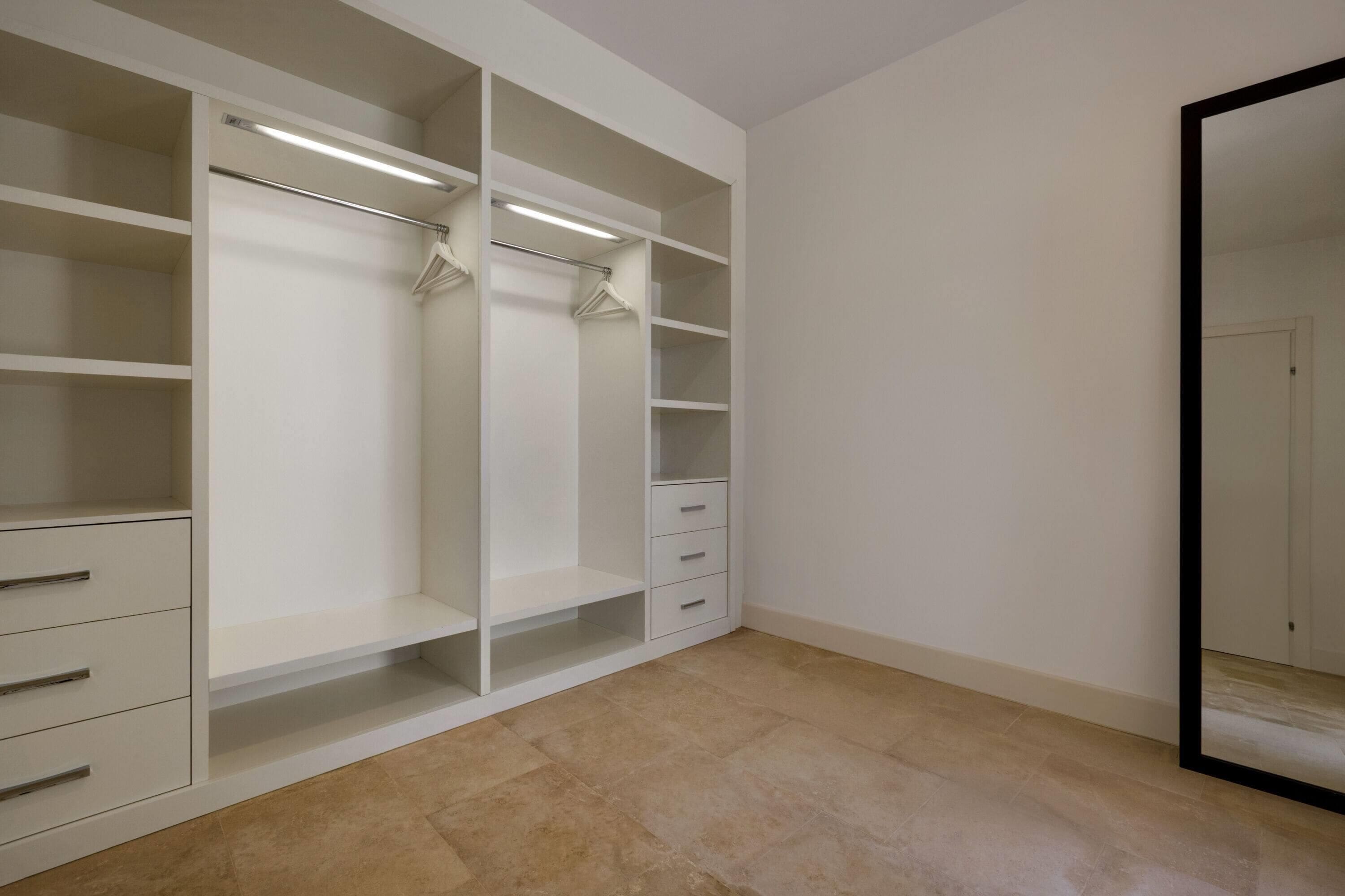 Ein begehbarer Kleiderschrank mit mehreren Regalen, Kleiderstangen und Schubladen.