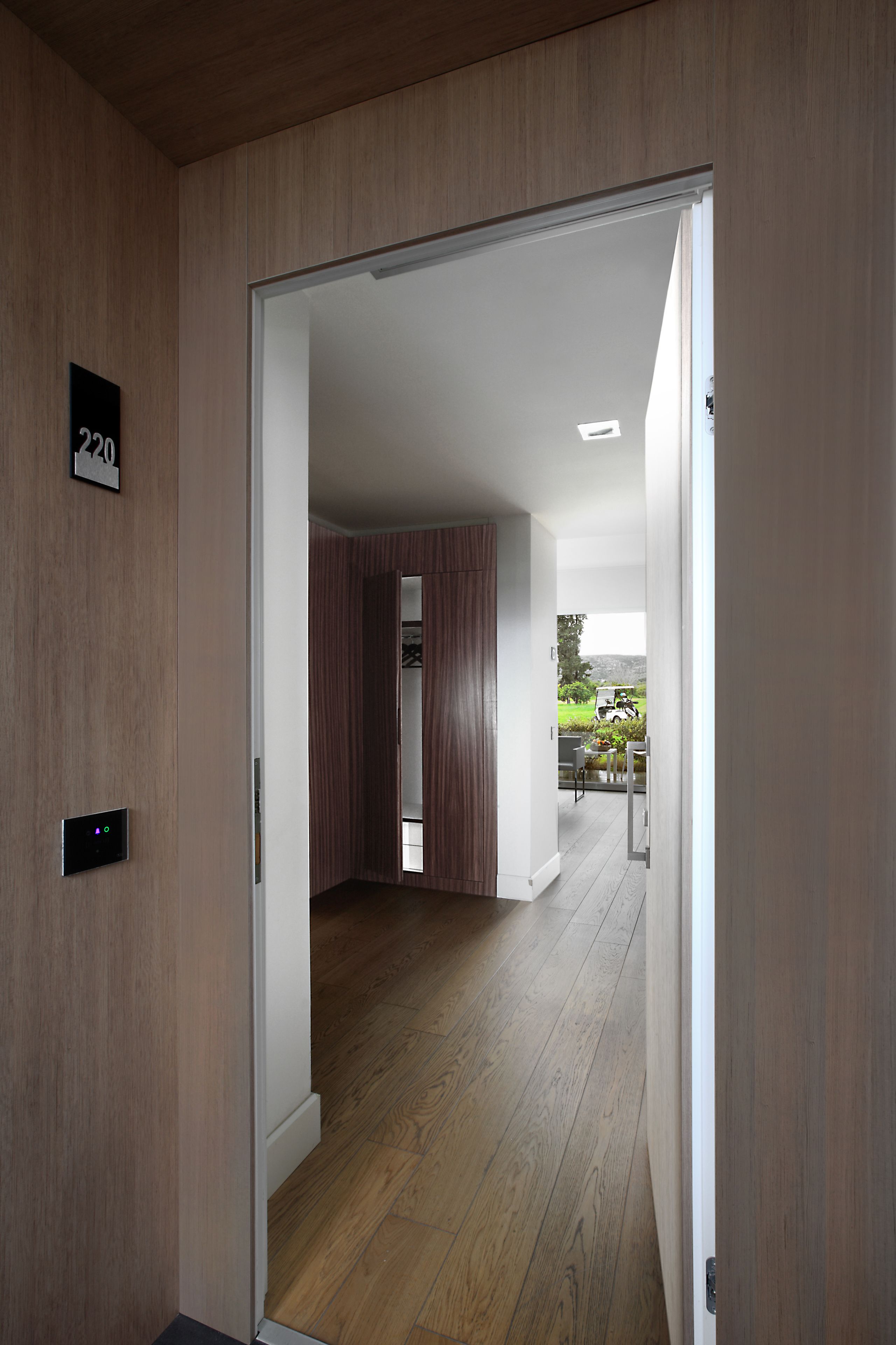 Ein modernes Hotelzimmer mit Holzboden, einer Schiebetür und Blick auf einen Garten.