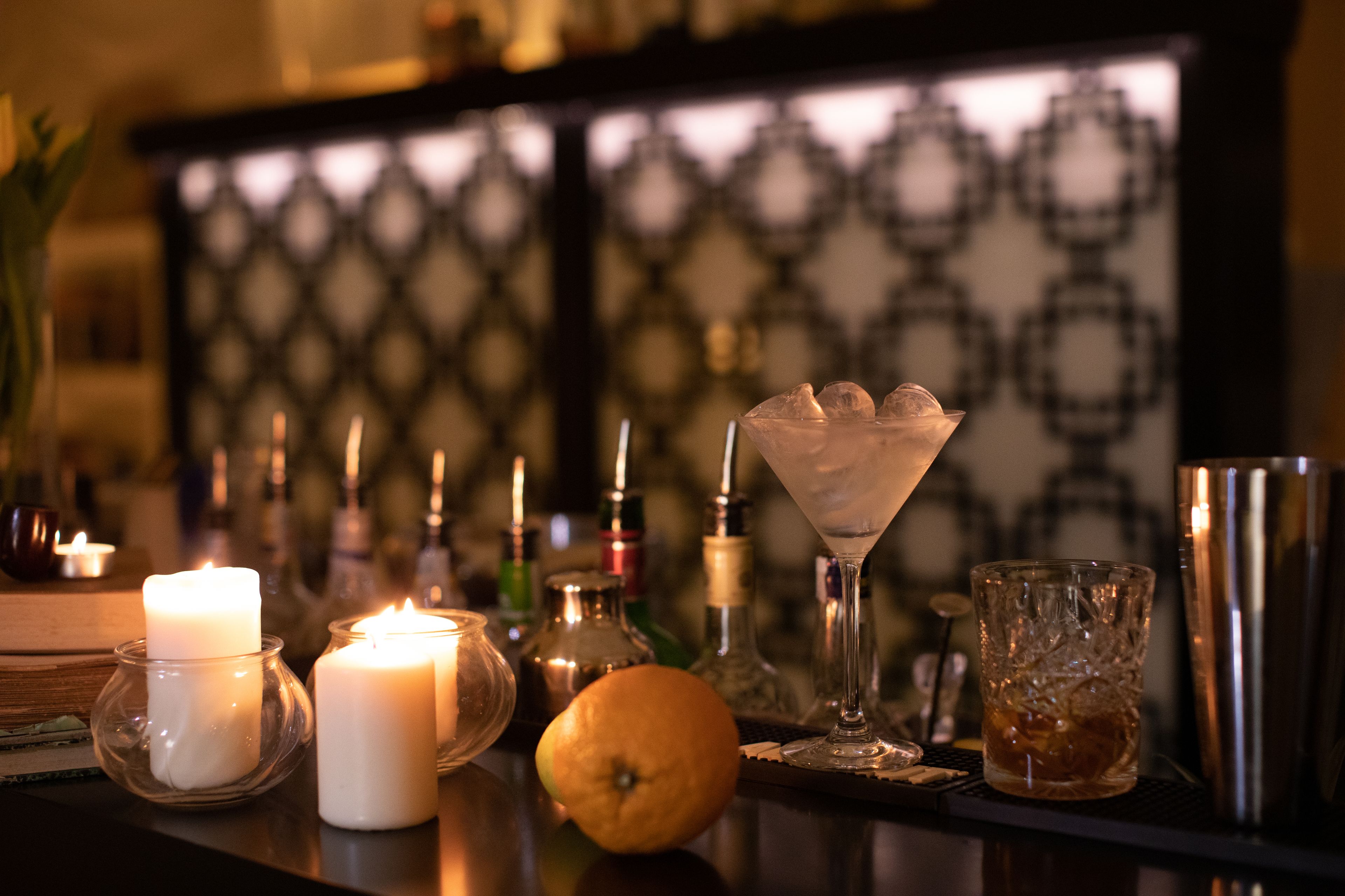 Un coin bar avec des bougies, un verre à martini et diverses bouteilles.
