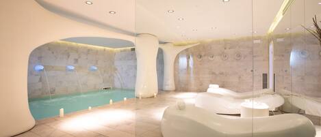 Un spa moderno con una amplia piscina interior, una zona de relajación independiente con hidromasaje y un mamparo de vidrio.
