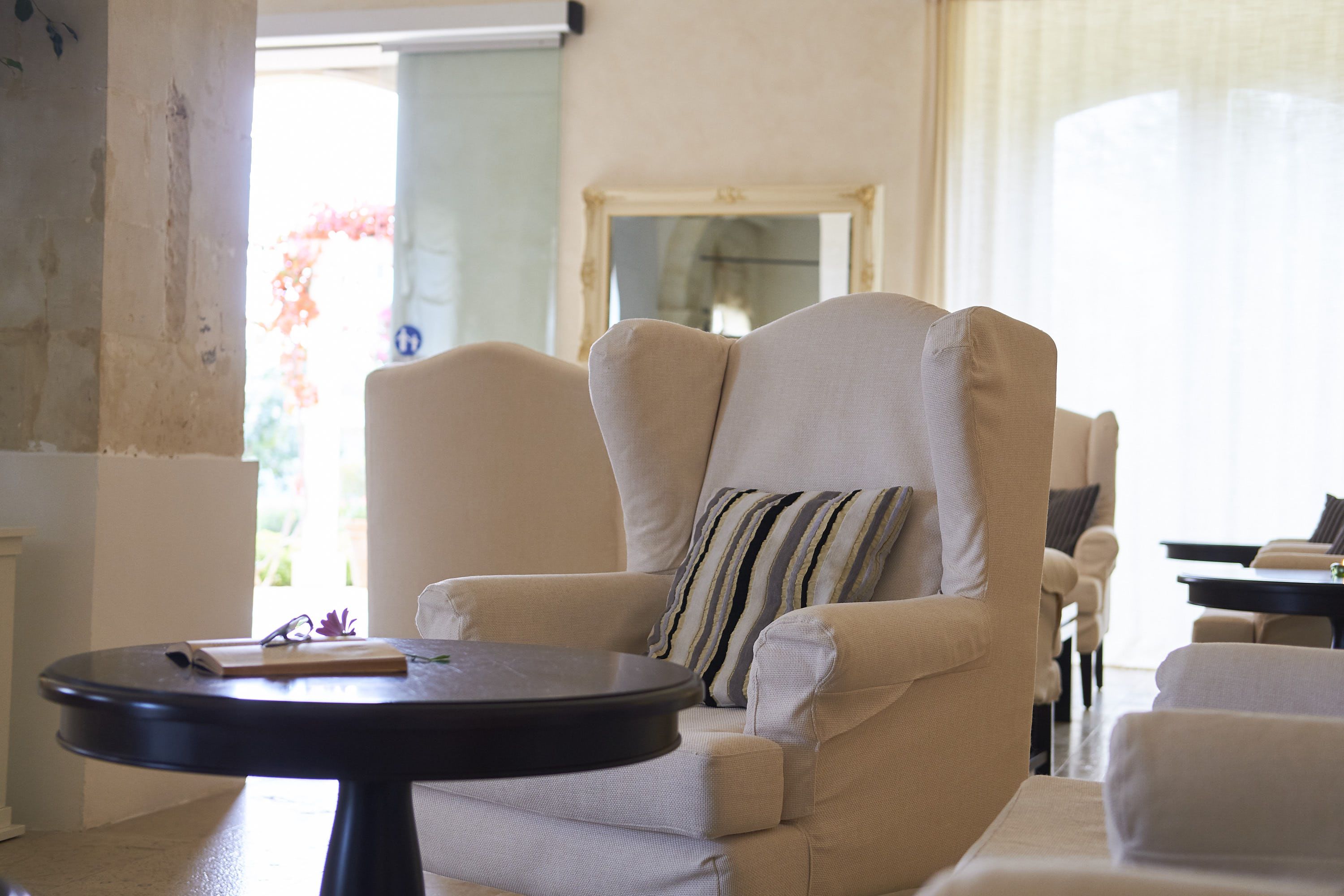 A living room with a beige armchair, a round black table, and a striped pillow.