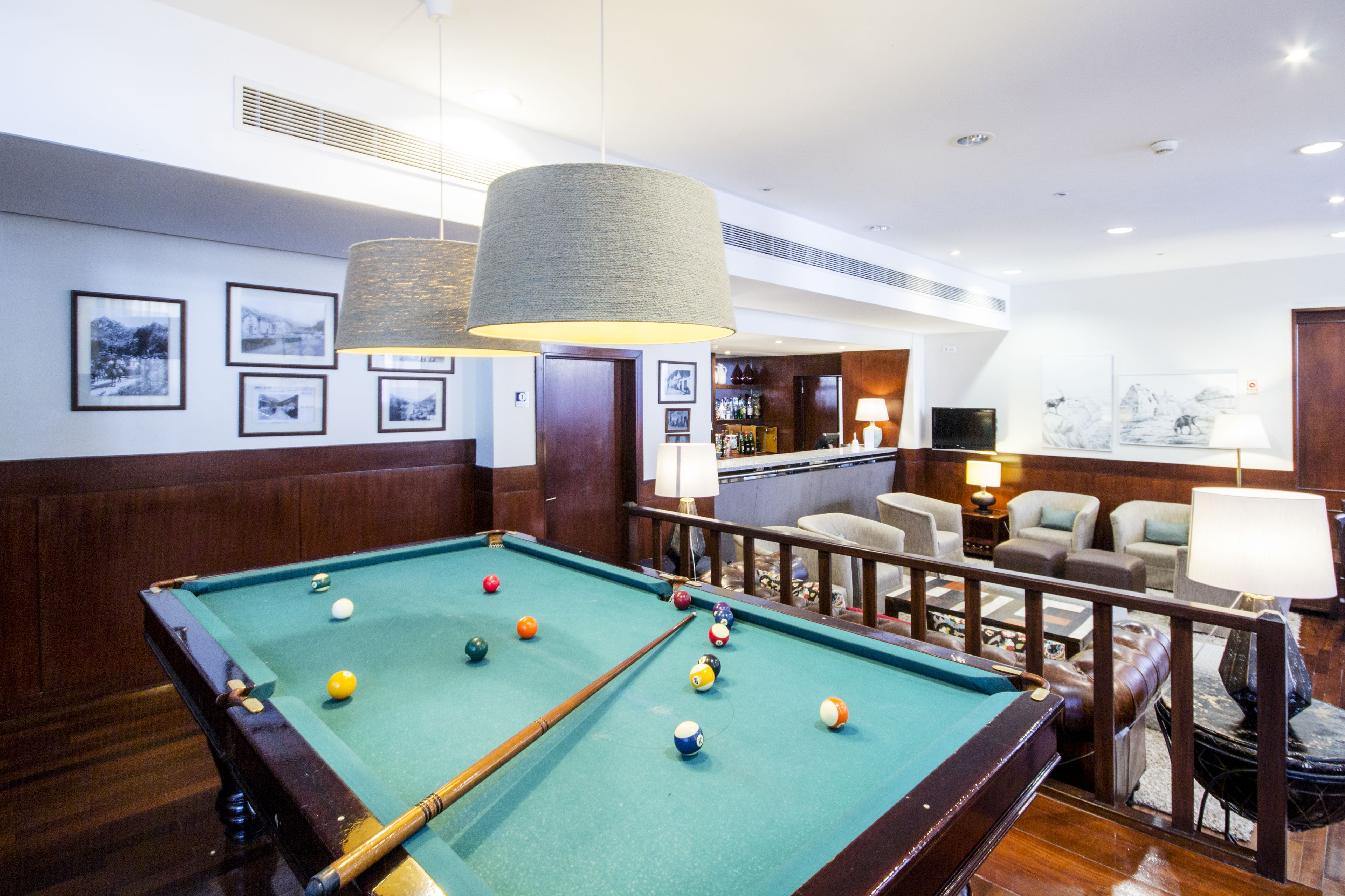 A pool table with balls, a bar area, and a seating area with couches and a TV.