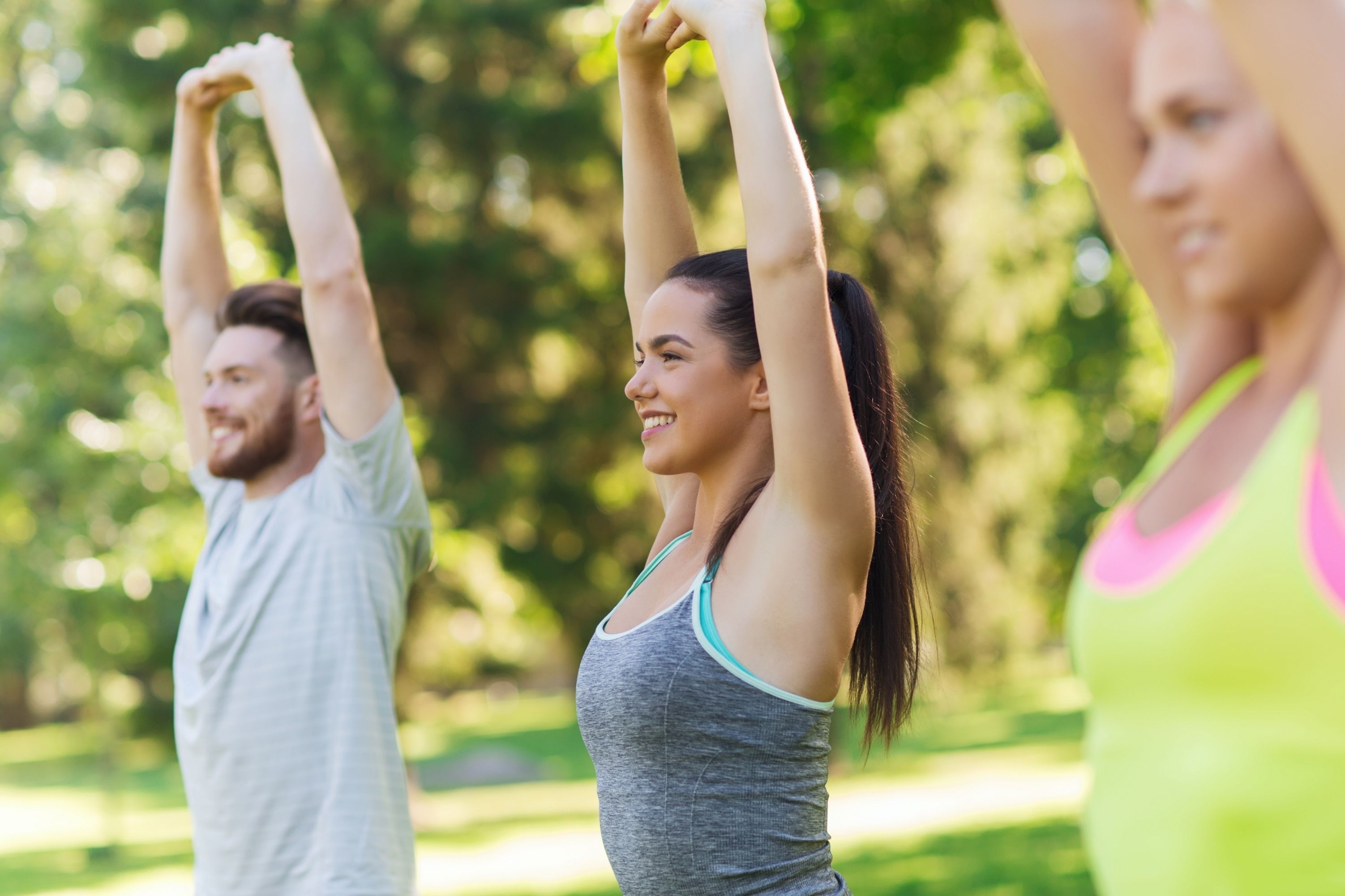 A group of people in a park performing a stretching exercise.