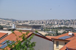 Un paisaje urbano con edificios residenciales, un edificio destacado con fachada moderna y paneles solares en los tejados.