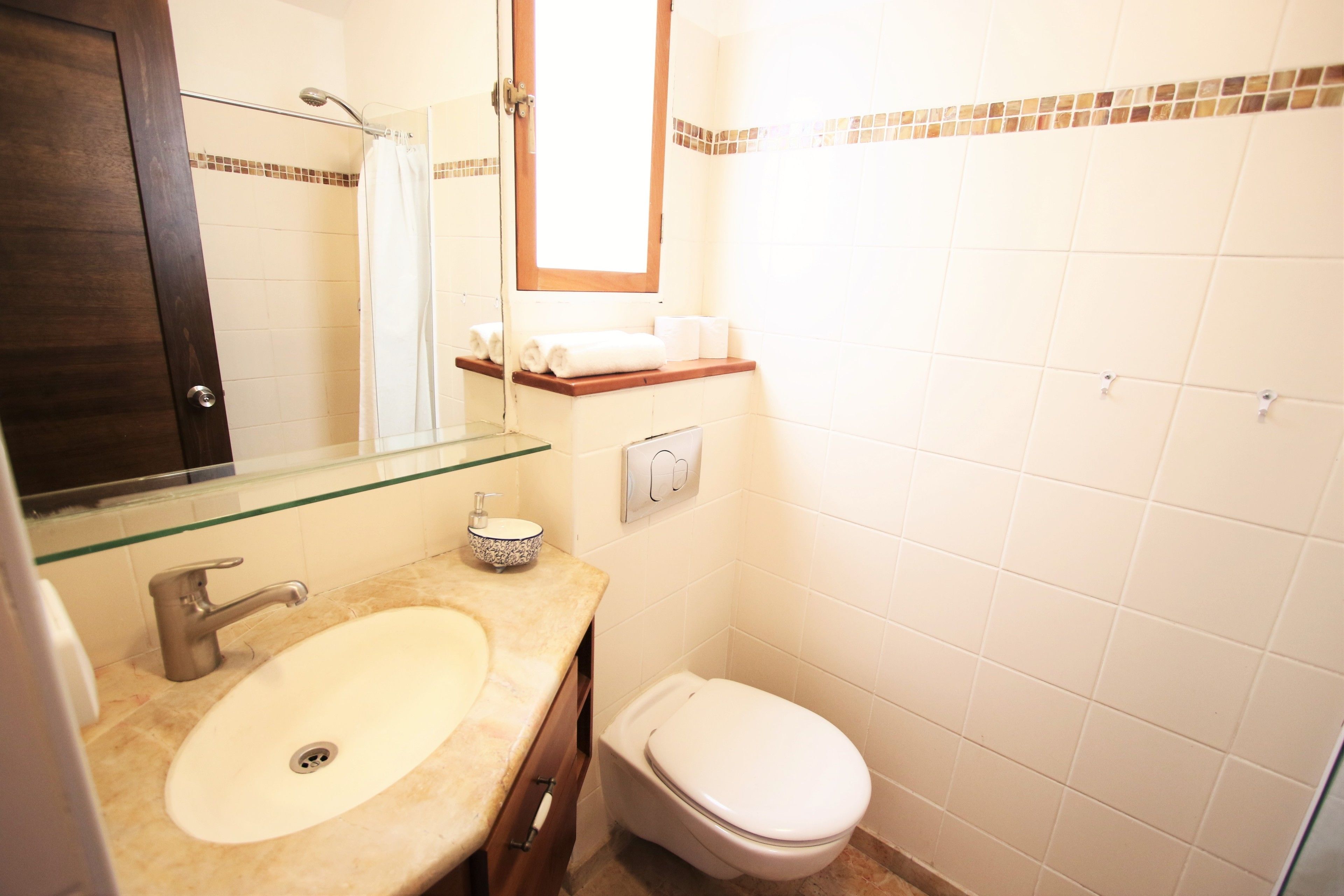A bathroom with a sink, mirror, toilet, and shower.