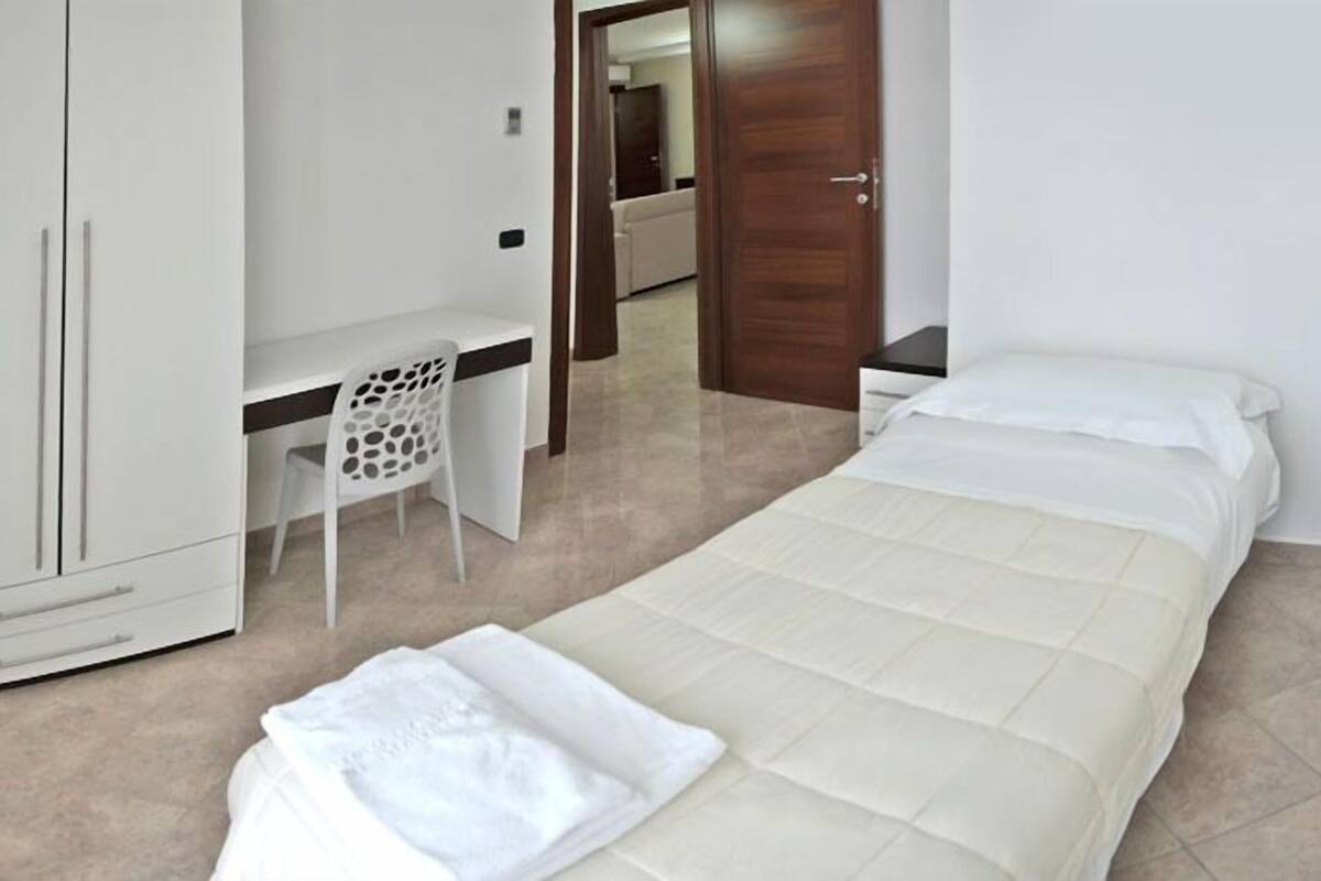 A bedroom with two beds, a desk, and a wardrobe.