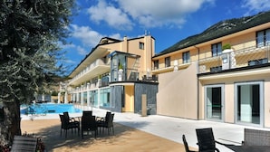 Un hotel moderno con piscina, zona de estar al aire libre y vistas a la montaña.