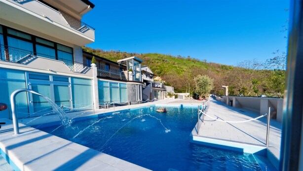 Una piscina con tobogán acuático, un puesto de socorrista y vistas a una ladera.