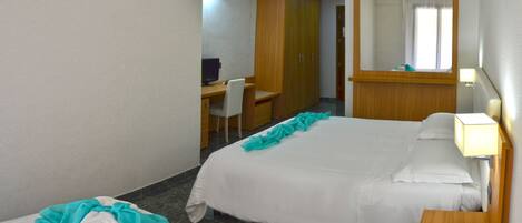 A hotel room with two beds, a desk, a chair, a mirror, and a nightstand.