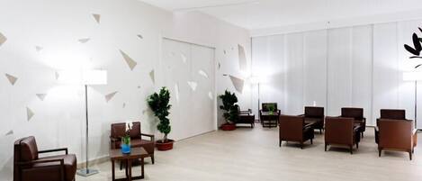 A modern waiting area with leather sofas, a coffee table, and potted plants.