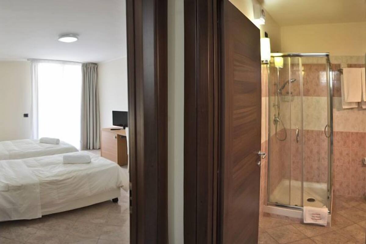 A hotel room with two beds, a shower, and a television.