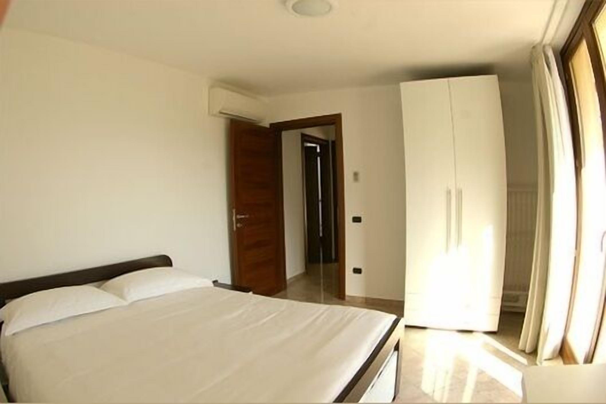 Une chambre d’hôtel comprenant un lit, une armoire et une porte donnant sur une autre pièce.