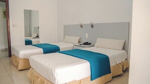 Habitació d'hotel amb dos llits, cada un amb un llençol blau i blanc, una taula de nit amb un telèfon i un mirall a la paret.