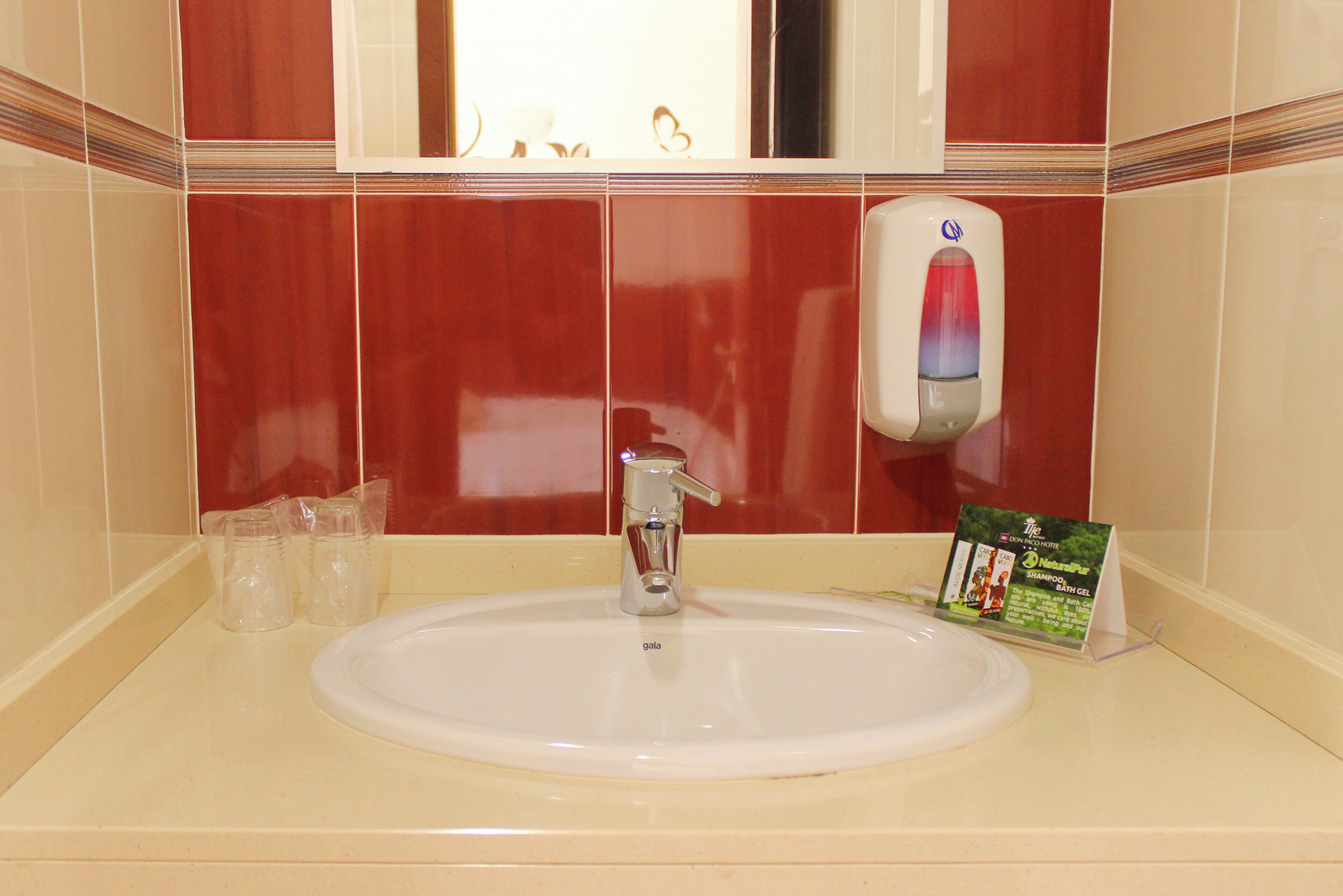 A bathroom sink with a hand soap dispenser and a promotional sign.