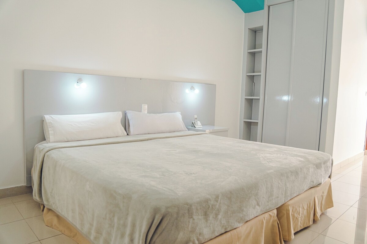 A large bed with a headboard, a bedside table, and a wardrobe.