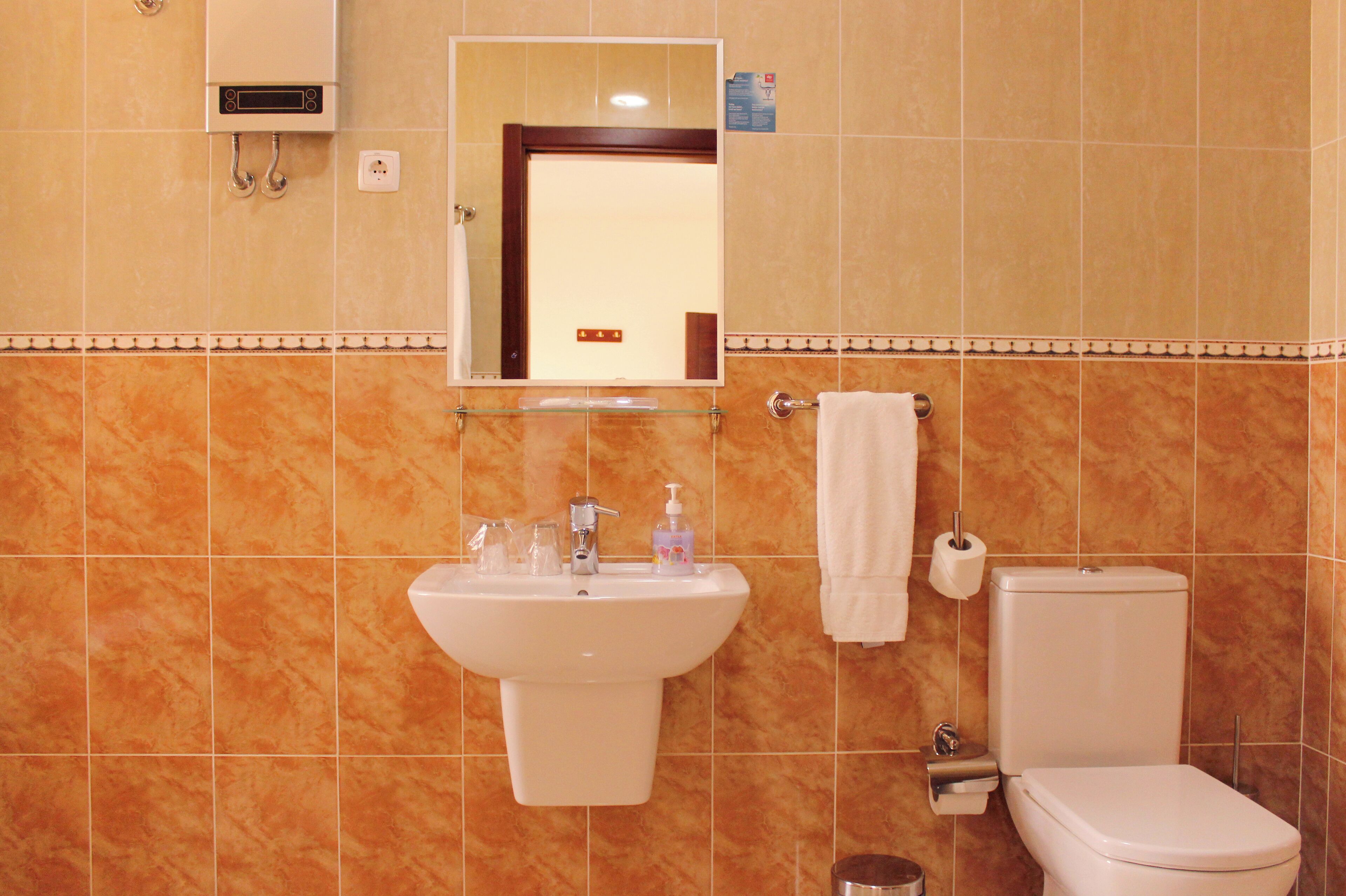 Une salle de bain équipée d’un lavabo, d’un miroir, de toilettes et d’un porte-serviettes.