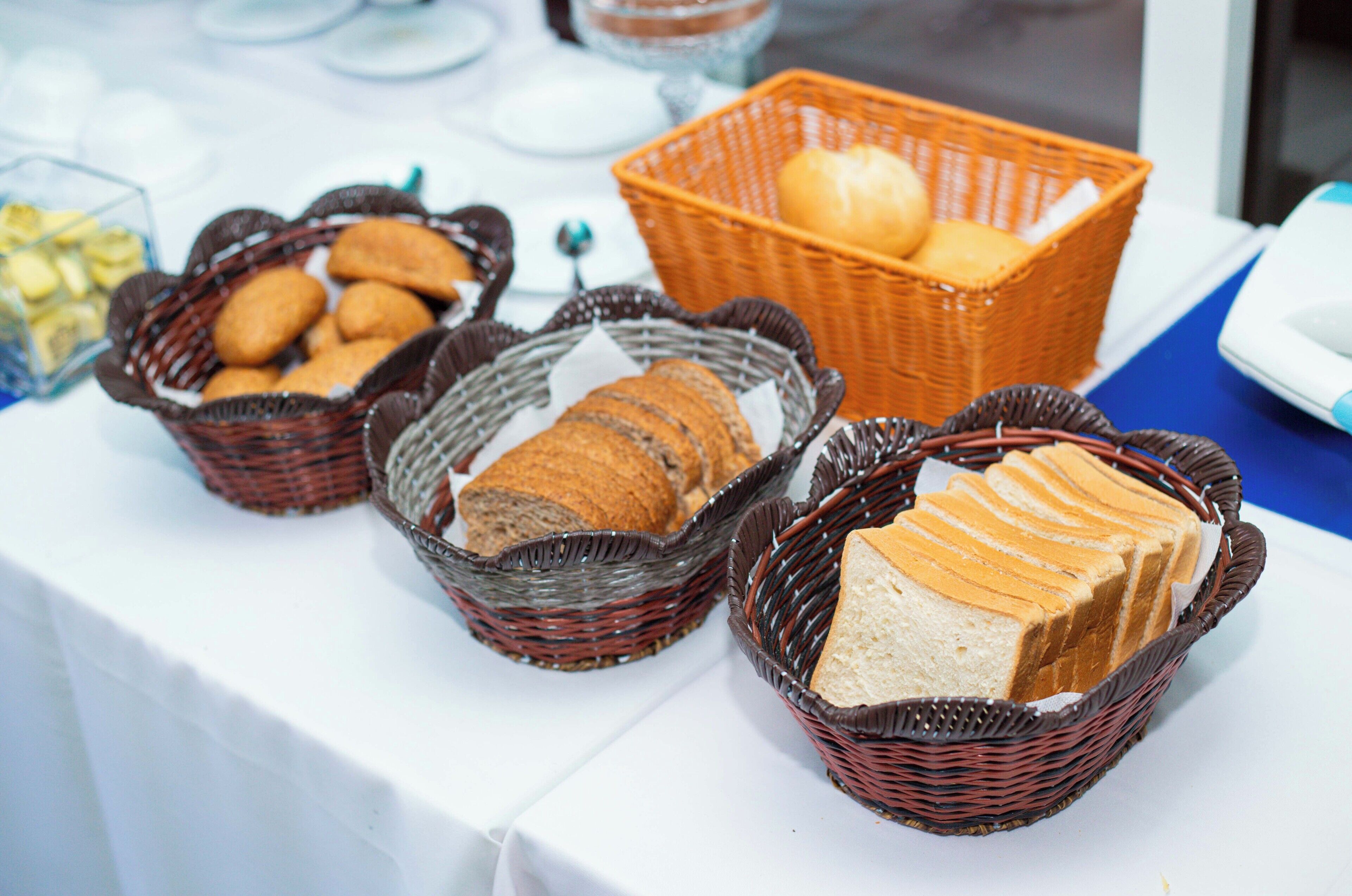 A table with baskets containing various breads and pastries.