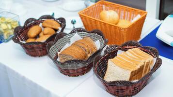 A table with baskets containing various breads and pastries.