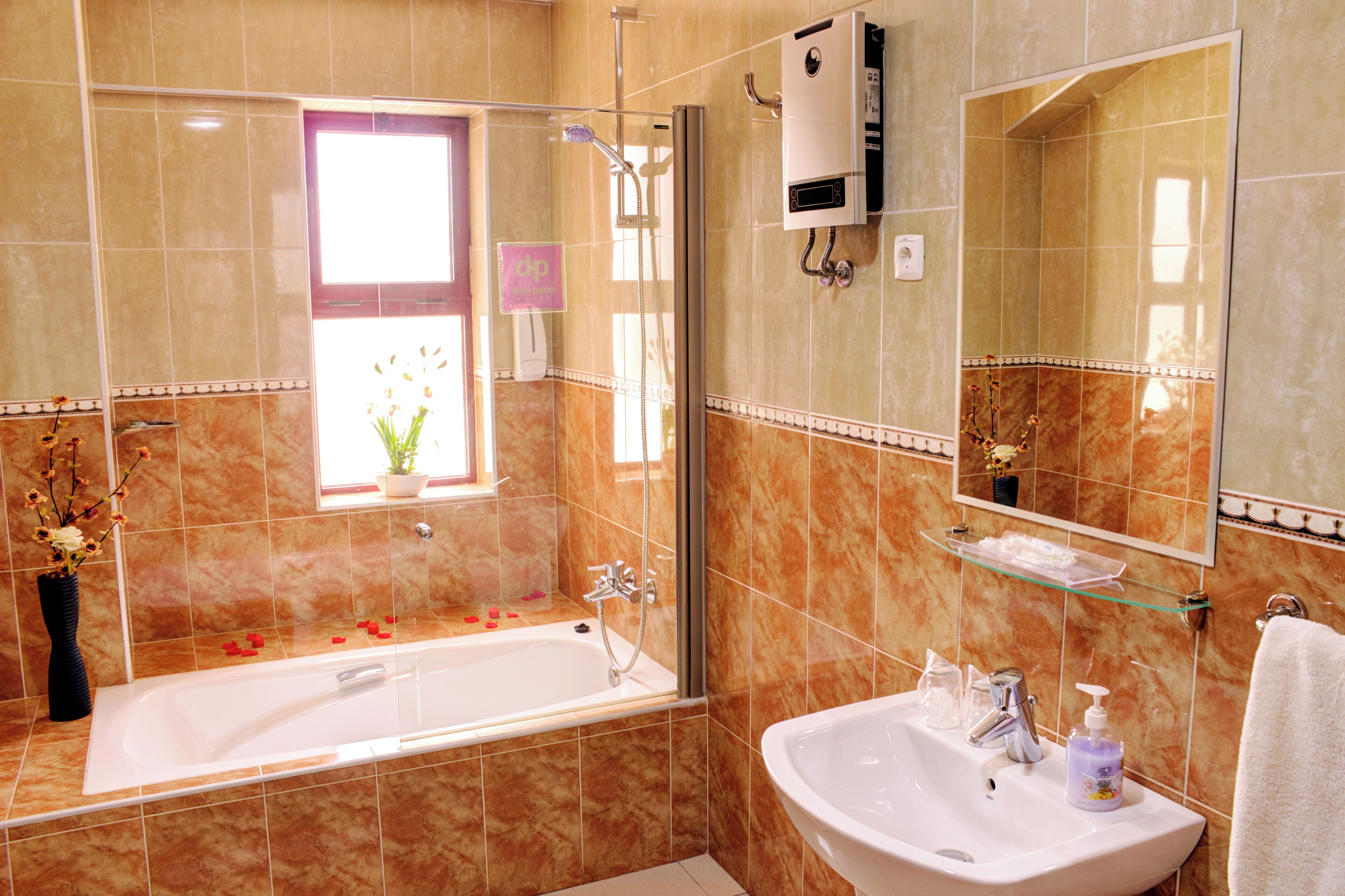 Un baño con bañera, lavamanos, cabina de ducha de vidrio, una ventana con planta y espejo.