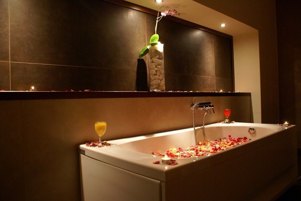 Un baño moderno con bañera, un espejo grande y un florero con una planta.
