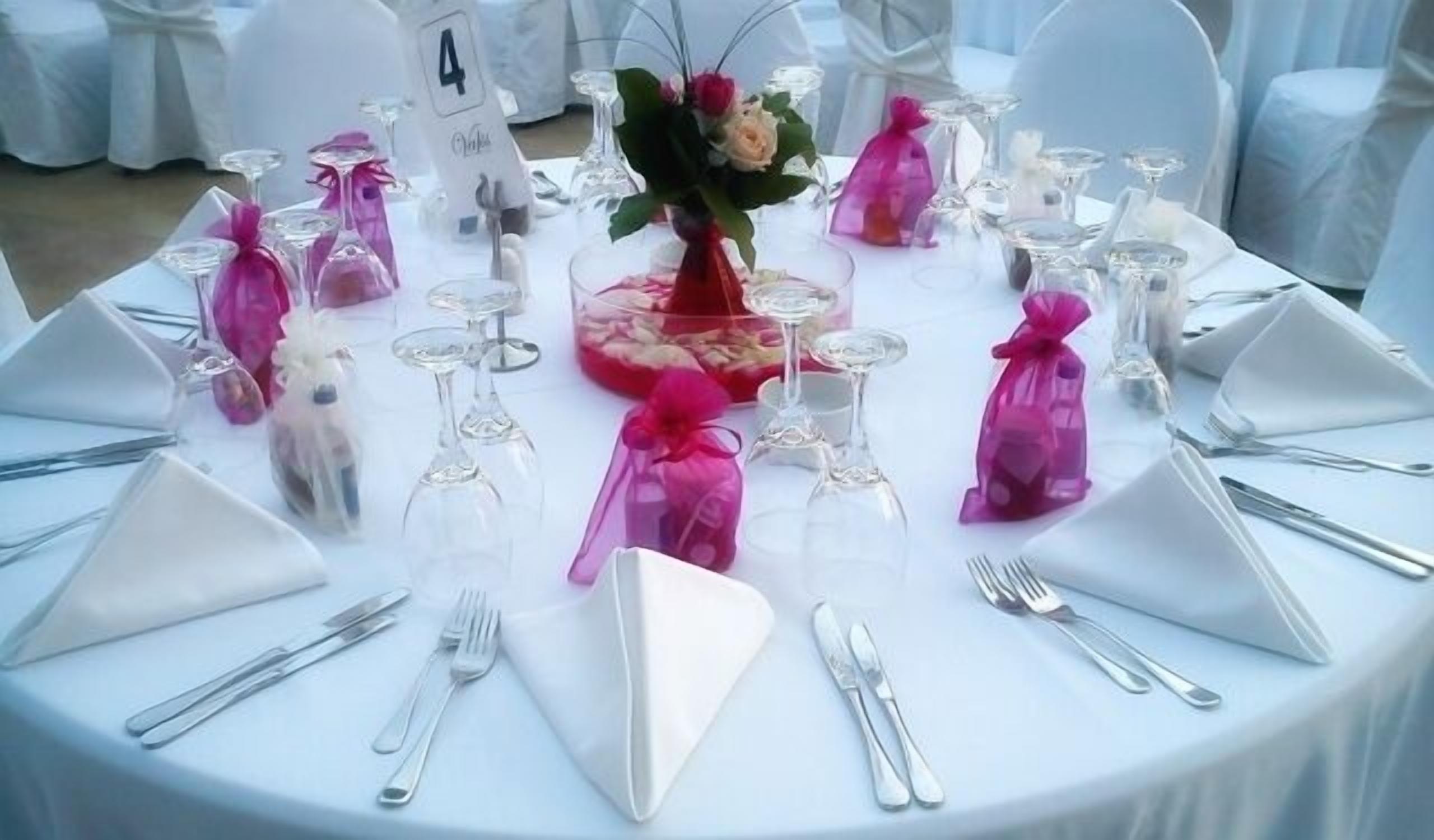 A round table set for a formal event with numbered place settings, clear glassware, and decorative centerpieces.