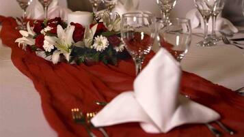 A table set with wine glasses, a candle, and a floral centerpiece.