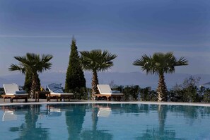 Alberca techada, alberca al aire libre y sombrillas en la alberca