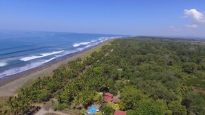 Un paisaje costero con playa, abundante vegetación y cielo azul despejado.