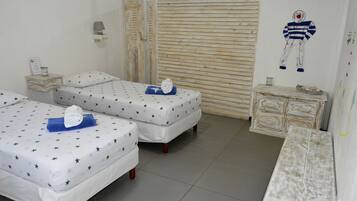 Una habitación con dos camas, cada una con ropa de cama estampada con motivos de estrellas, una mesita de noche pequeña con una lámpara y una obra de arte colgada en la pared.