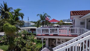 A white building with a red roof, a balcony with white railings, and a flag. - Breakaway Inn (Lauderdale-by-the-Sea)