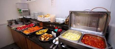 Un buffet con una varietà di cibi, tra cui frutta, verdura e piatti pronti.