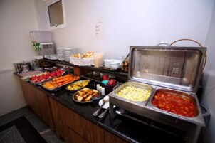 Un buffet con una varietà di cibi, tra cui frutta, verdura e piatti pronti.