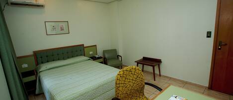 Una habitación de hotel con una cama, una silla, una mesa con un menú y una puerta.