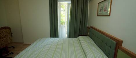 A hotel room with a bed, a chair, a bedside table with a phone, and a picture on the wall.