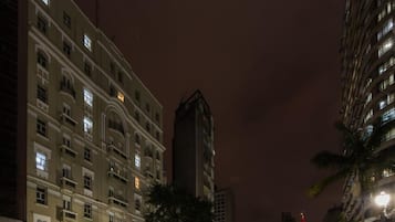 Un edificio de varios pisos con ventanas iluminadas y una calle frente a él.