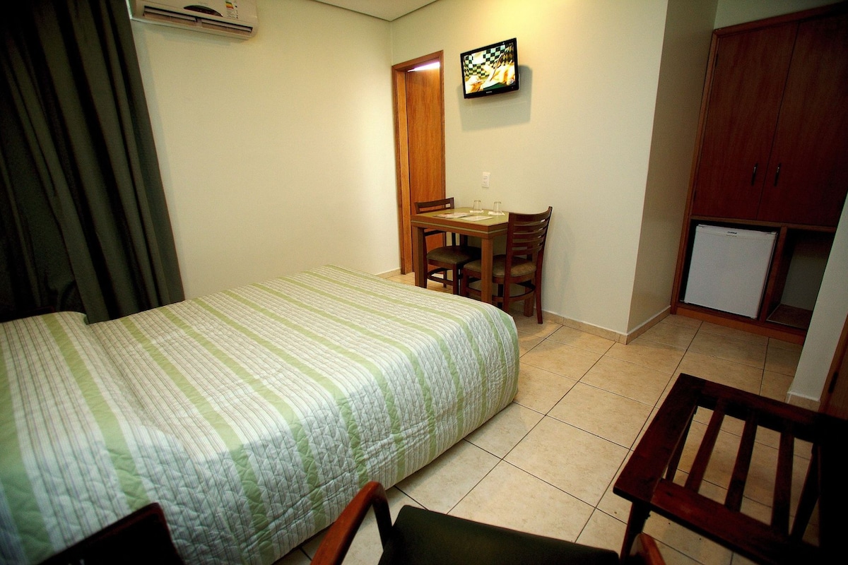 Une petite chambre à coucher, bien rangée, avec un lit, un bureau et une chaise.