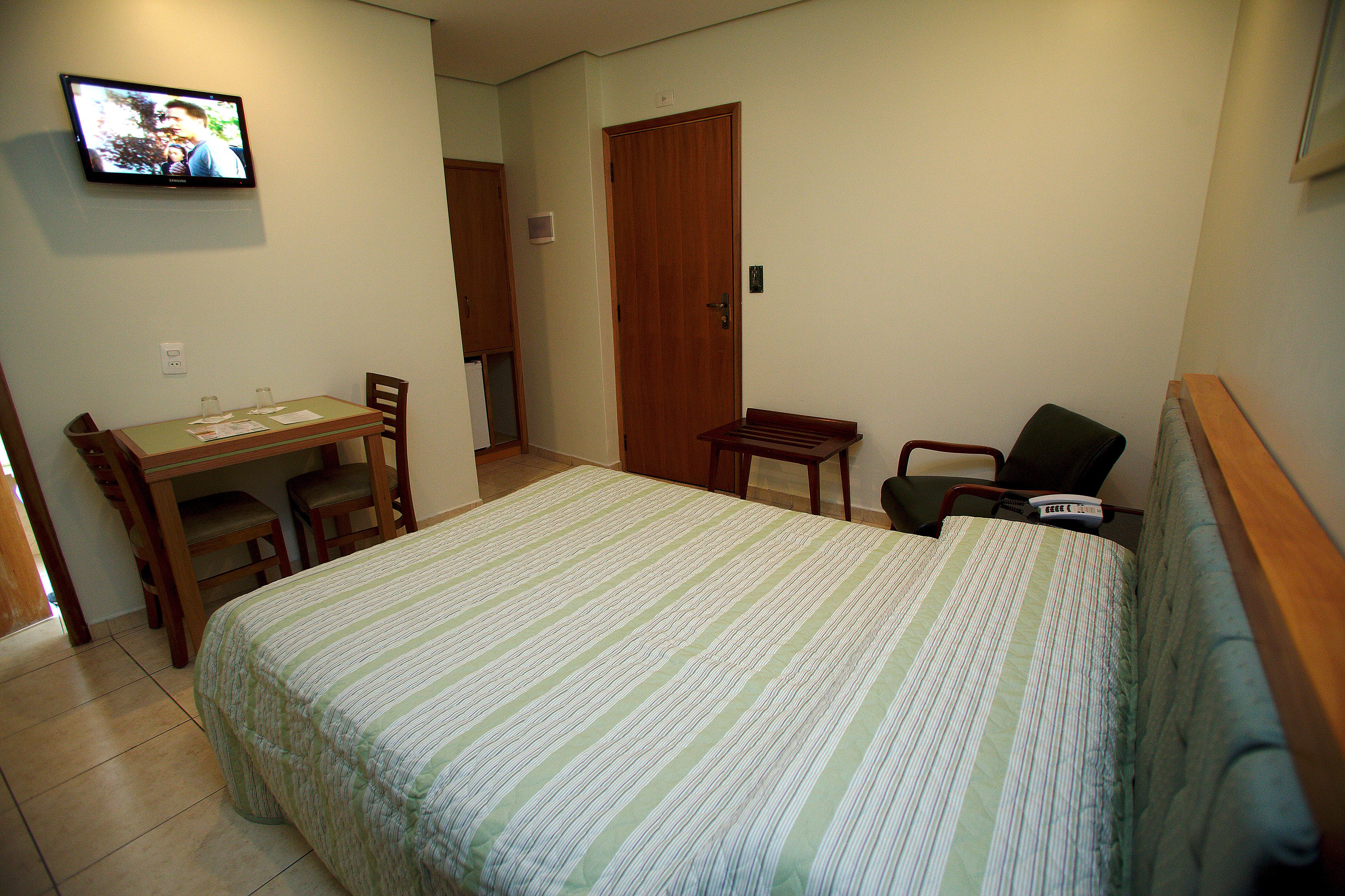 A small, clean room with a bed, a desk, and a chair.