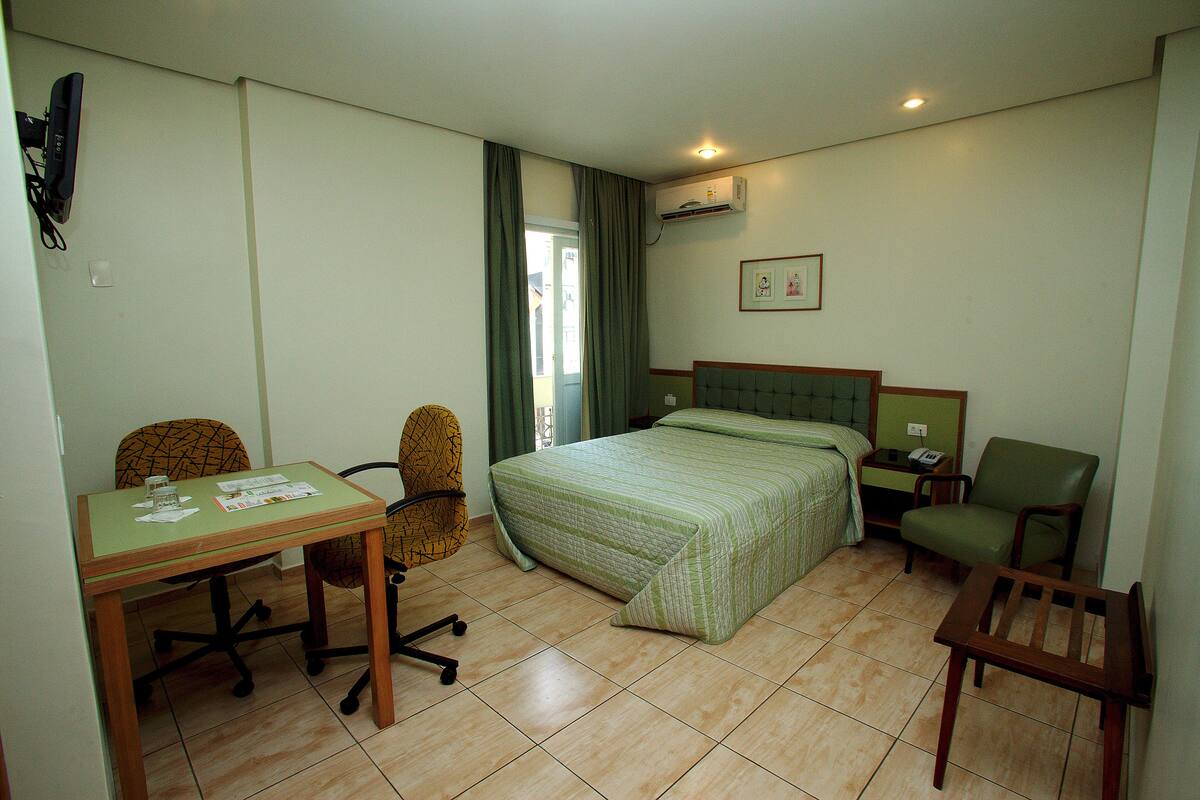 Une chambre d’hôtel avec un lit, un bureau, une chaise et une petite table.