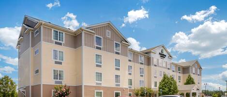 A multi-story hotel with a modern design, featuring a parking lot with several cars.