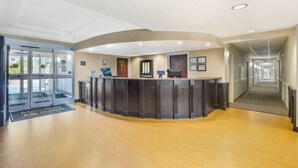 Un área de recepción con un mostrador curvo, puertas de vidrio y un pasillo que conduce a una escalera.