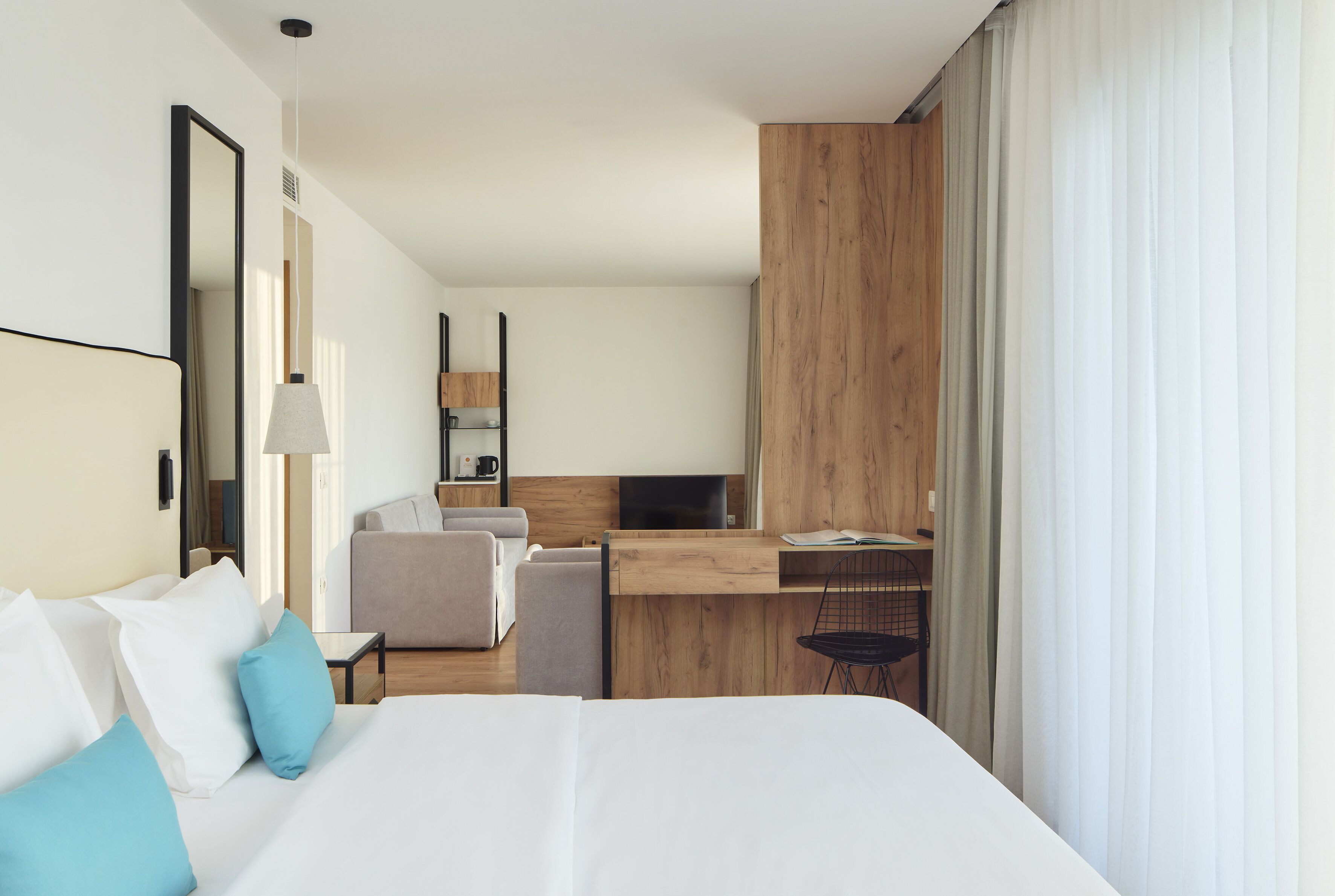 Une chambre d’hôtel avec un grand lit, un bureau, une chaise et un téléviseur.