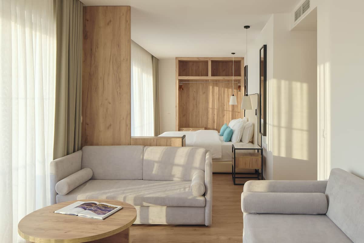 A modern living room with a sofa, a coffee table, and a bed with a wooden headboard.
