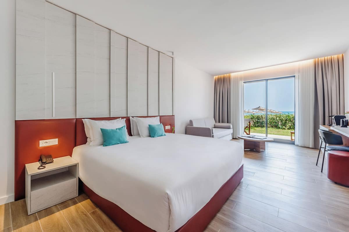 A hotel room with a large bed, a desk, and a view of the outdoors.