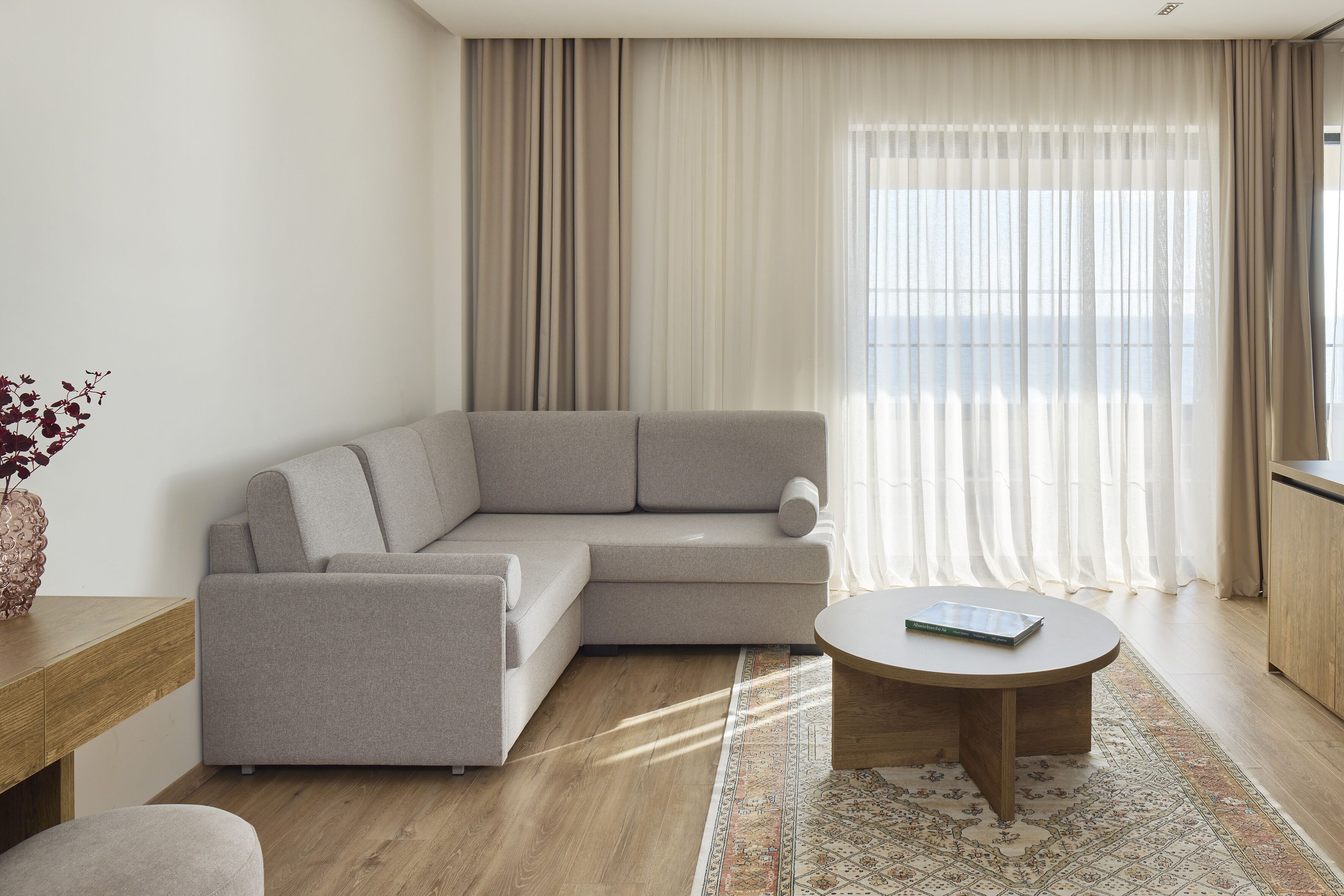 A modern living room with a grey sectional sofa, a round coffee table, and a patterned rug.