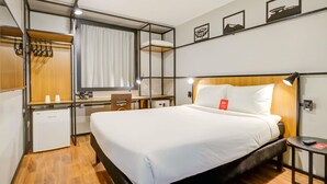 Une chambre d’hôtel équipée d’un lit, d’un bureau, d’une chaise et d’un petit réfrigérateur.