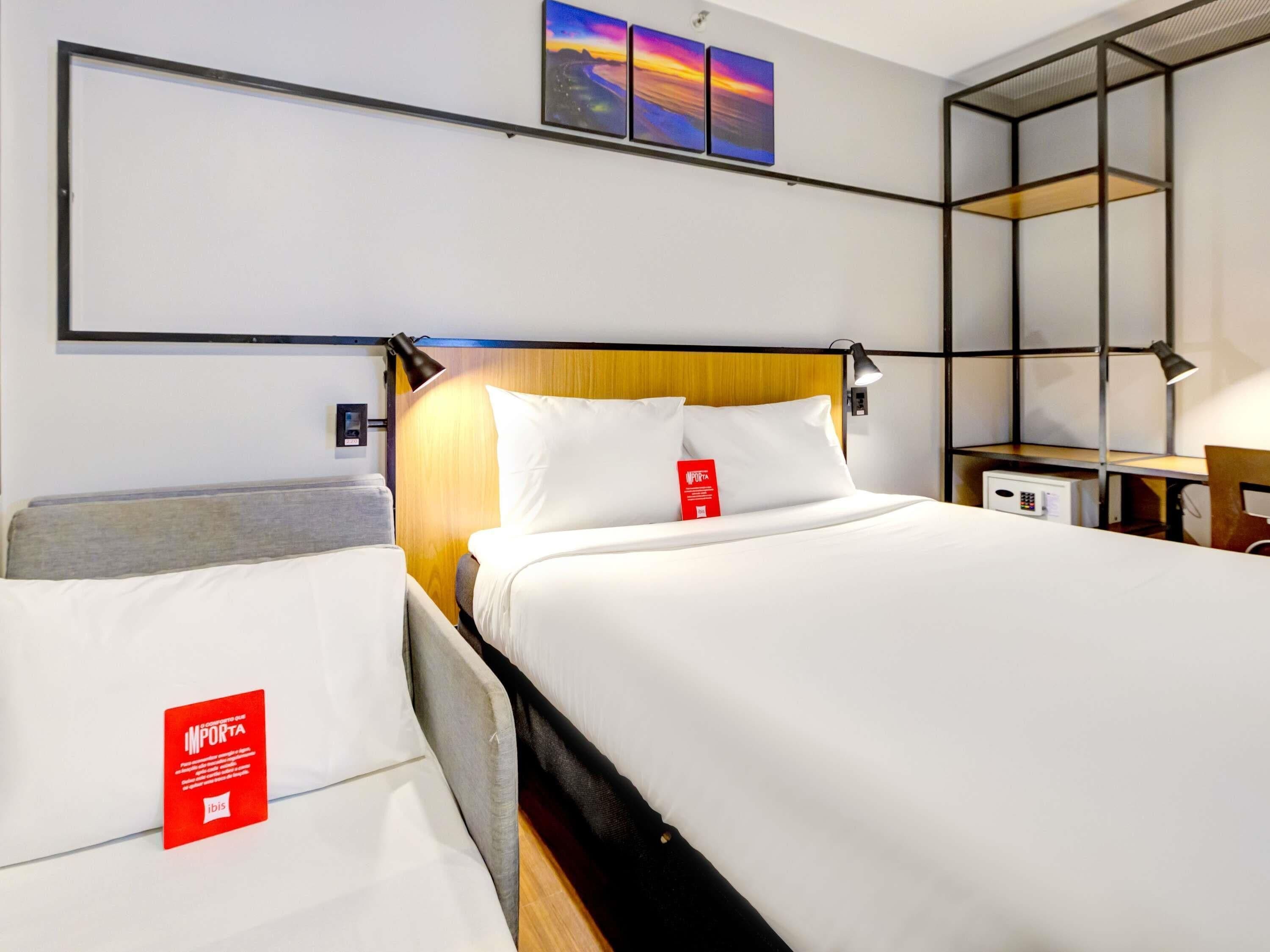 A hotel room with a bed, a desk, and a shelf unit.